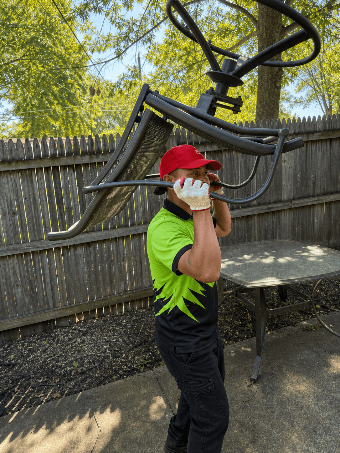 Wee Haul crew member carrying old metal patio furniture off a backyard patio