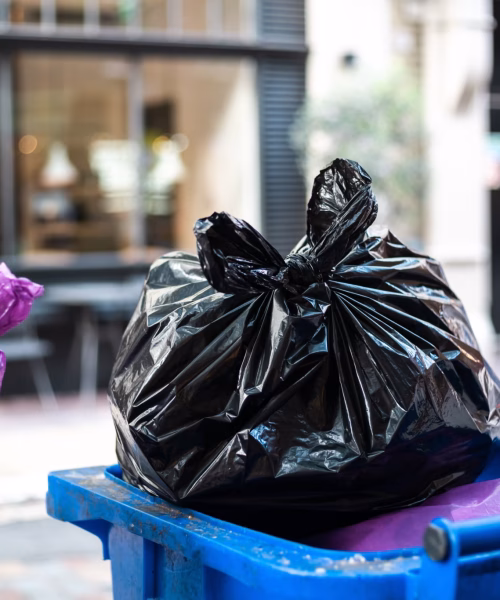And black bags of trash on a garbage bin during daytime Purple and black bags of trash on a garbage bin during daytime
